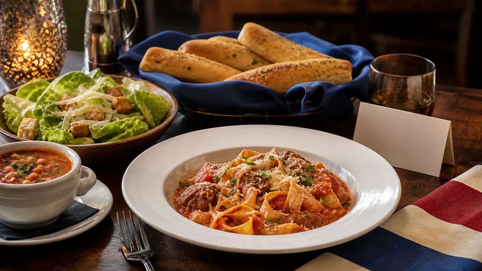 A respectful holiday dining table with pasta, soup, salad and breadsticks